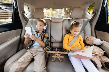Kinder mit Buch und Hörbuch bei langer Autofahrt